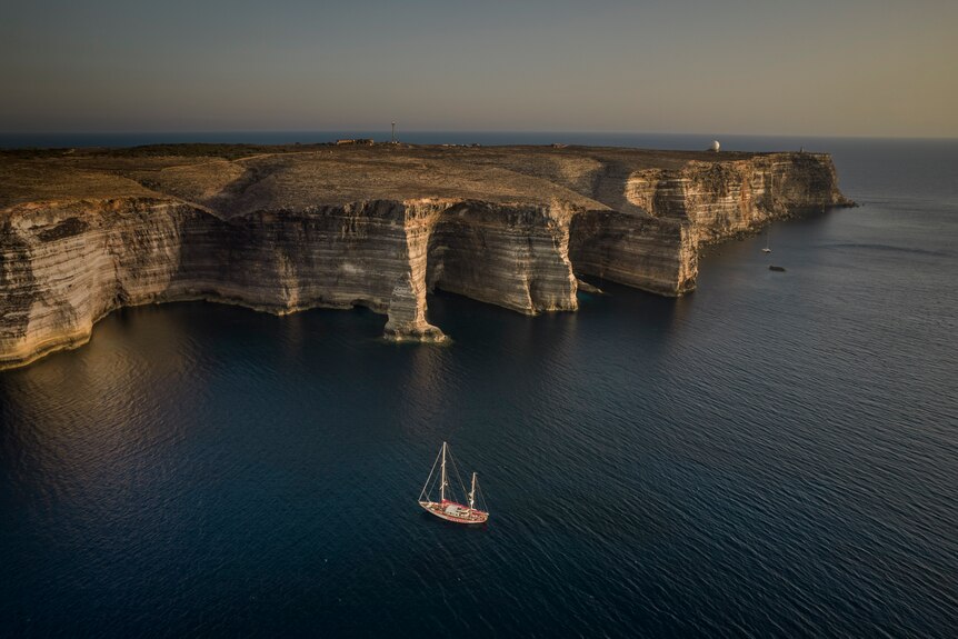 A yacht next to cliffs.