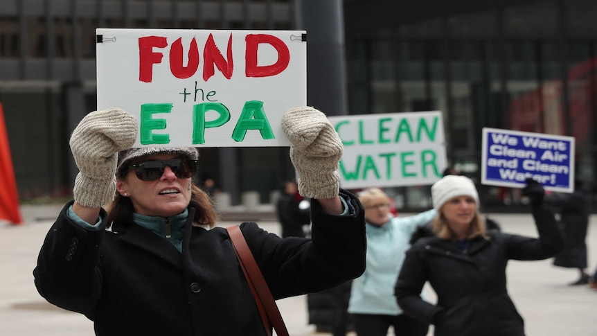 A protester holds a sign reading "Fund the EPA"