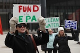 A protester holds a sign reading "Fund the EPA"