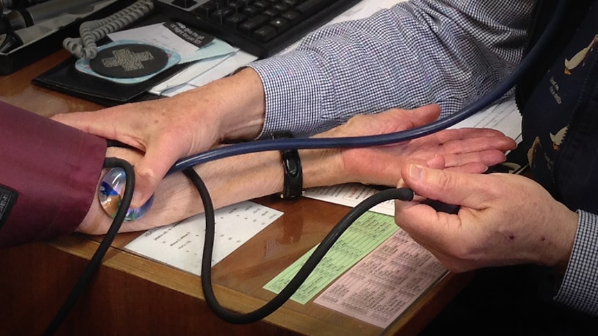 Close up of doctor taking patient's pulse using stethoscope.