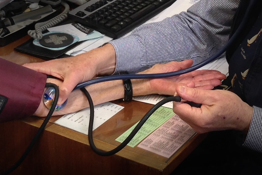 Close up of doctor taking patient's pulse using stethoscope.