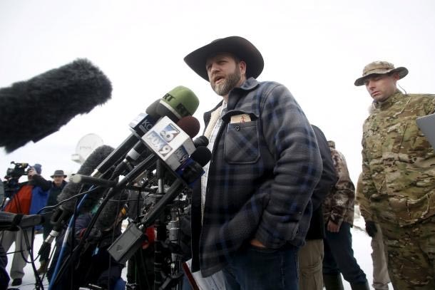 Low down angle of Ammon Bundy speaking in front of microphones.