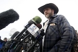 Low down angle of Ammon Bundy speaking in front of microphones.