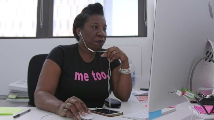 Tarana Burke sits at her computer with earphones on.