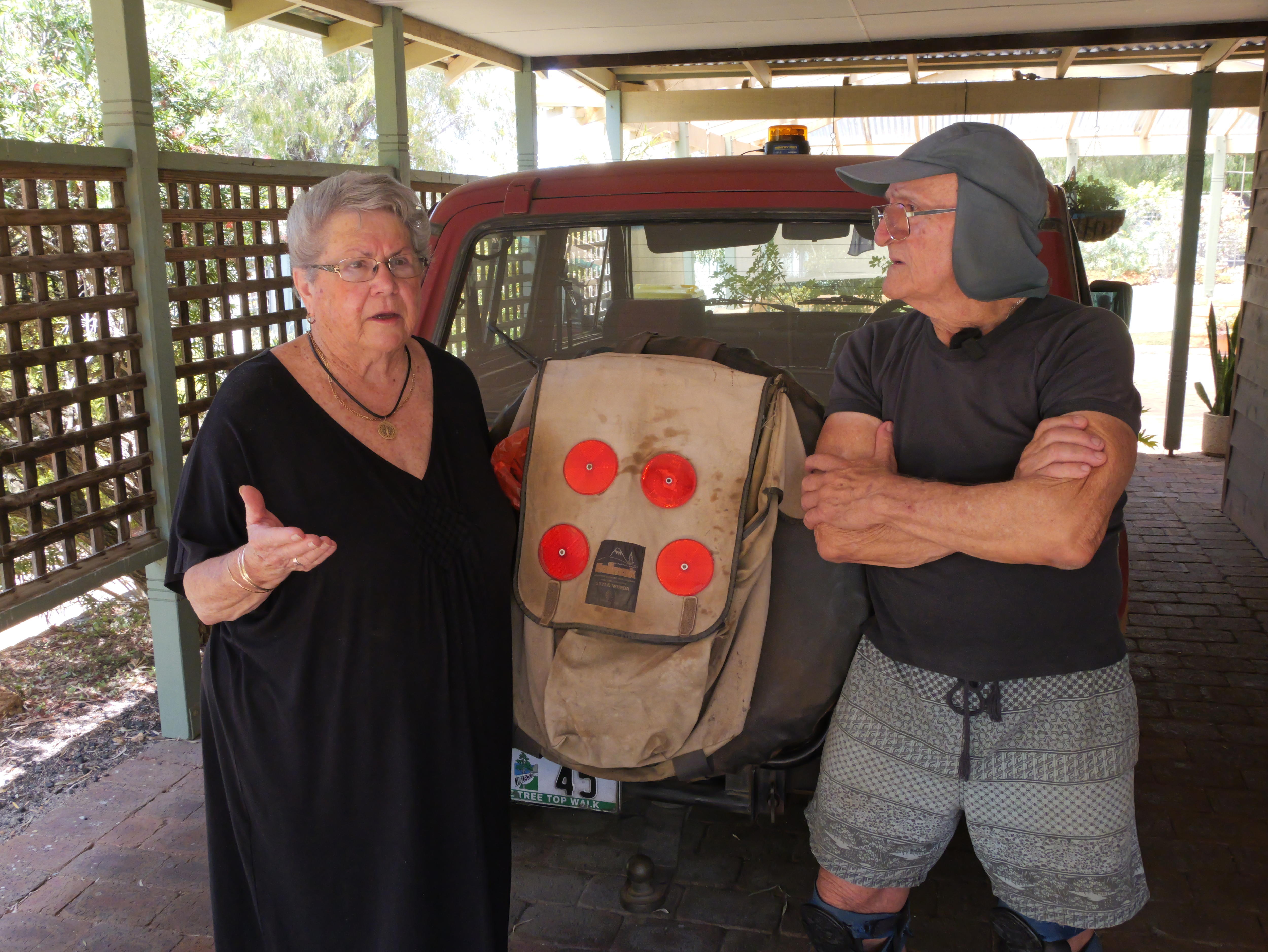 Un hombre y una mujer parados frente a un auto viejo