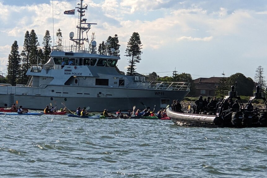 A NSW police boat surrounds a group of kayakers 