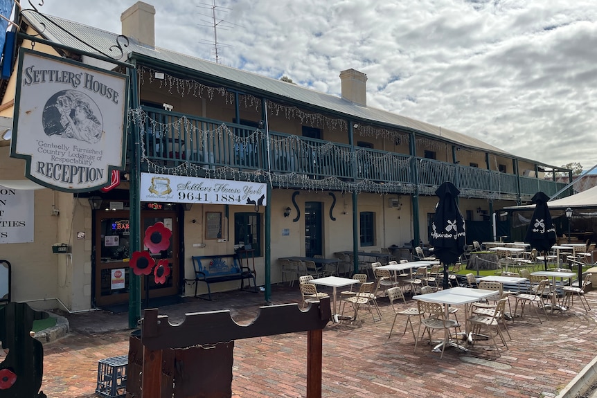 An outside shot of the Settlers Hotel in York, including an outdoor patio with chairs and seats and a green balcony