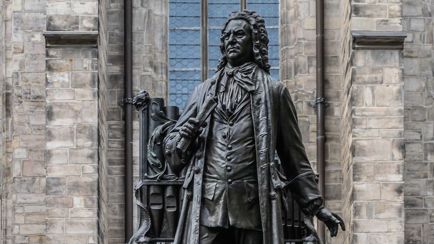 A close-up photograph of J.S. Bach's statue outside St. Thomas's Church in Leipzig.