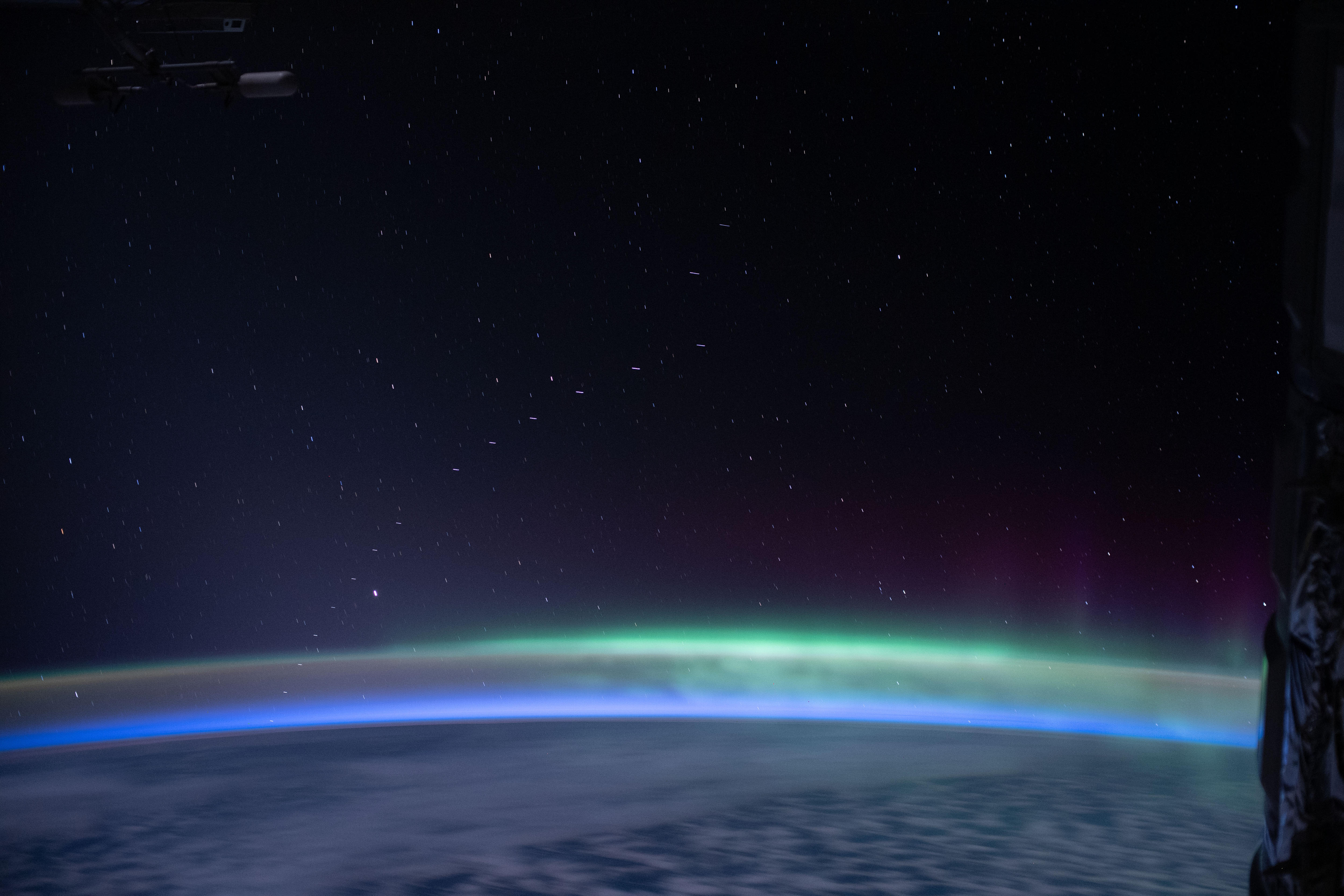 A line of satellites and the Southern Aurora above the Earth. 