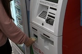 A woman inserting a 100 dollar note into a Bitcoin ATM