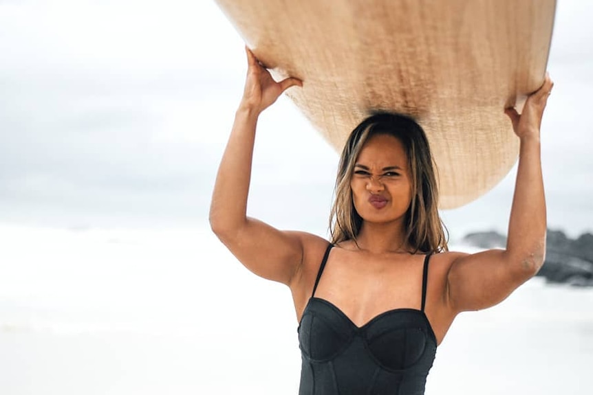 woman holding surfboard over her head