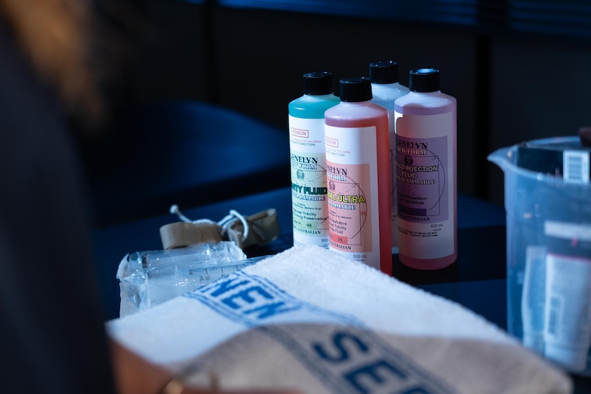 Bottles of surgical chemicals sit on a table next to a white and blue towel