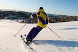 A person in yellow and purple snow gear skiing down a snow-covered mountain.