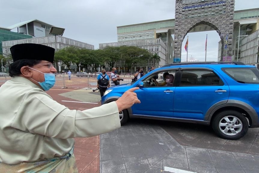 Tengku Adnan Tengku Mansor waving at a car driving through.