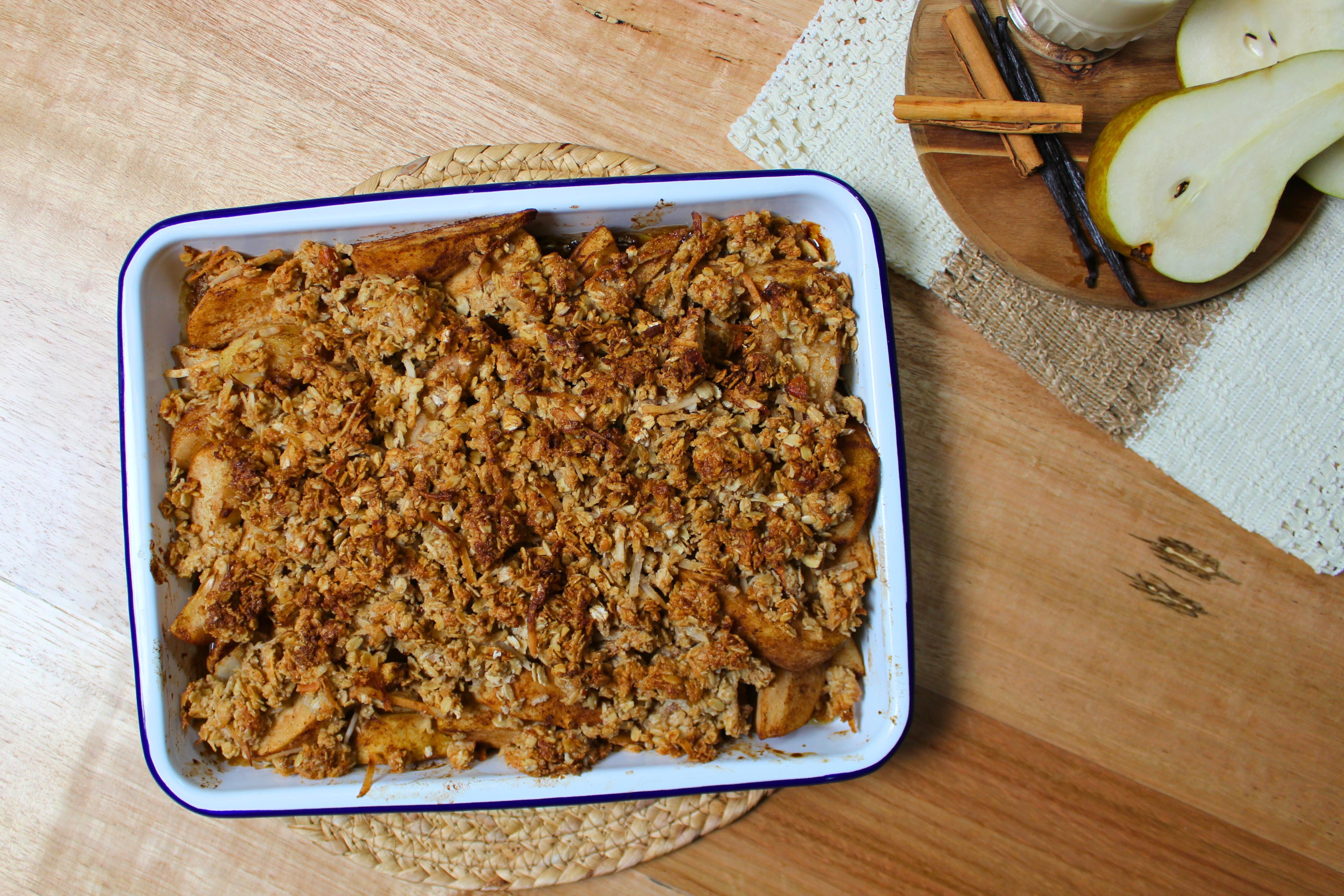 Freshly baked pear and coconut crumble in an enamel baking dish.