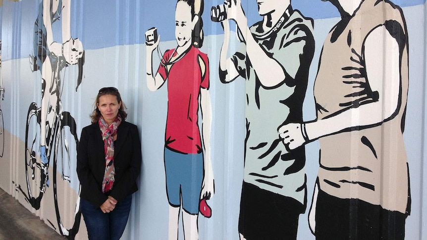 Kerri Karayan, beside a mural on Annerley Road at Dutton Park dedicated to her husband, Leslie