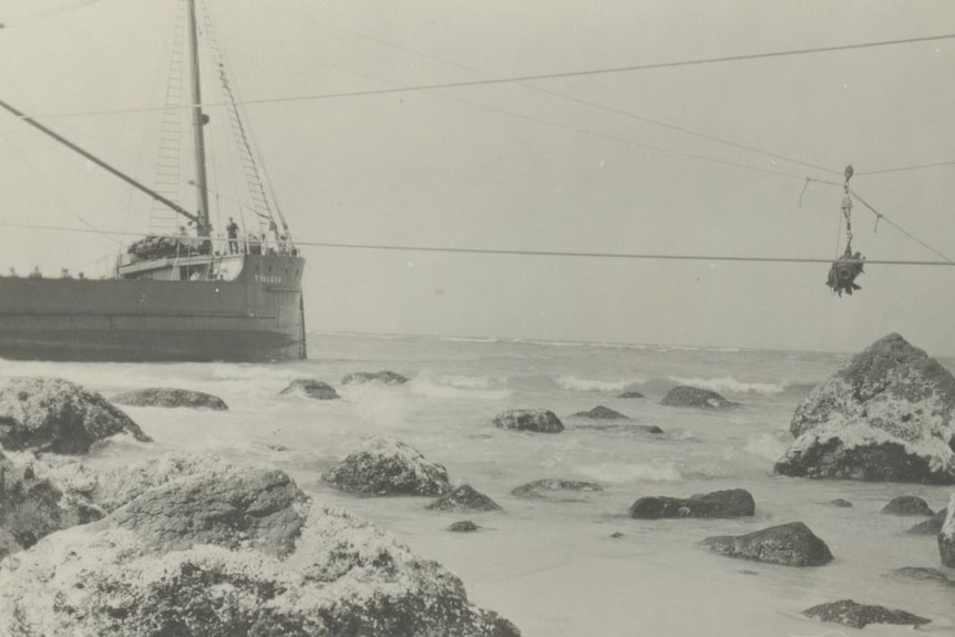 old picture of old ship agrounds and rescue line with person on it