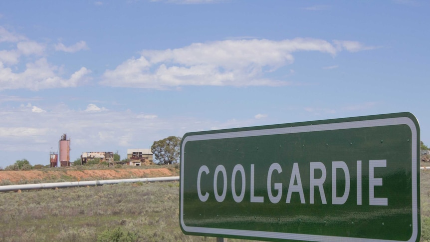 Image of an abandoned mine site on the outskirts of Coolgardie, Western Australia, with the town's entry sign in the foreground.