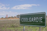 Image of an abandoned mine site on the outskirts of Coolgardie, Western Australia, with the town's entry sign in the foreground.