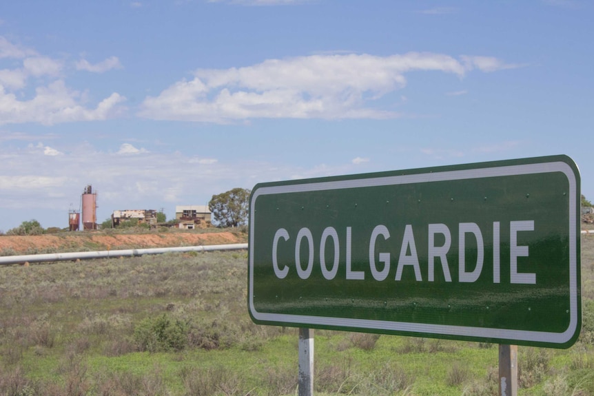 Image of an abandoned mine site on the outskirts of Coolgardie, Western Australia, with the town's entry sign in the foreground.