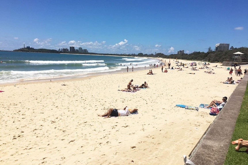 People relax in the sun on Mooloolaba beach on Queensland's Sunshine Coast