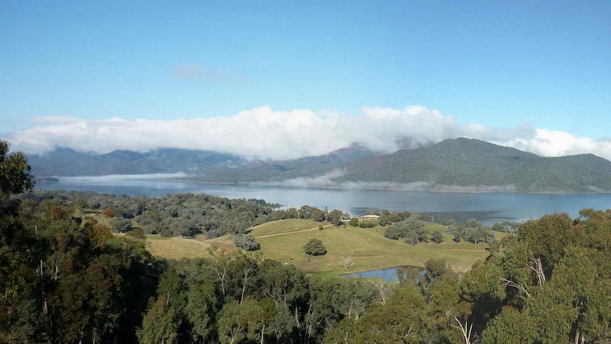 A big blue lake surrounded by mountains with a blue sky and white clouds