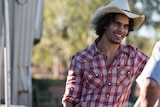Indigenous actor Mark Coles Smith, wearing a hat and a checked shirt.