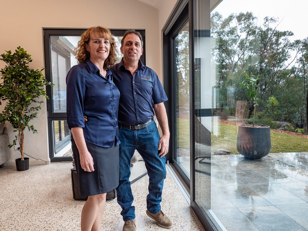 A man and woman standing in a house in front of a big glass door