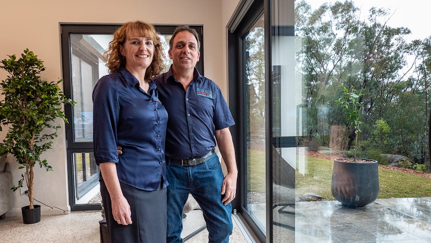 A man and woman standing in a house in front of a big glass door