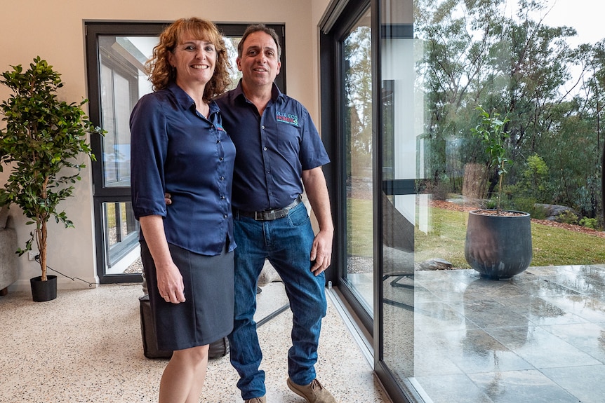 A man and woman standing in a house in front of a big glass door