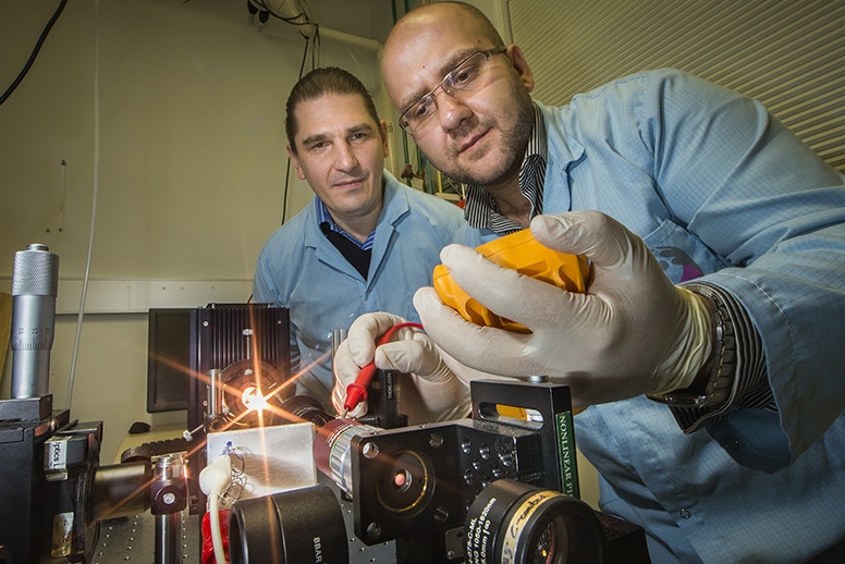 A researcher looks over the shoulder of his colleague who is working on a nanoparticle machine.