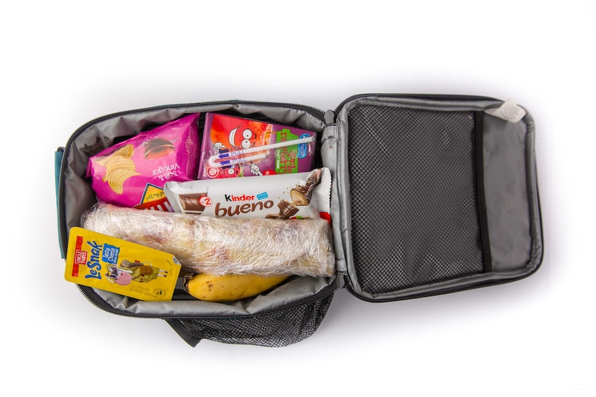 Homemade zatar bread, potato chips, cheese dip and biscuits, a chocolate bar, a banana and a fruit box in a cooler bag.