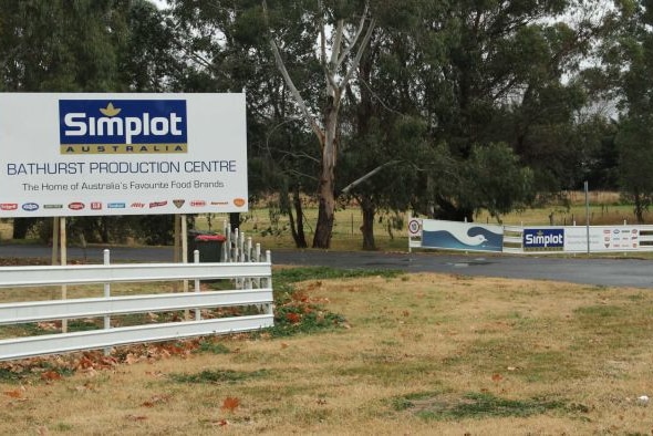A sign for "Simplot Australian Bathurst production centre" on a fence at the entry to a factory
