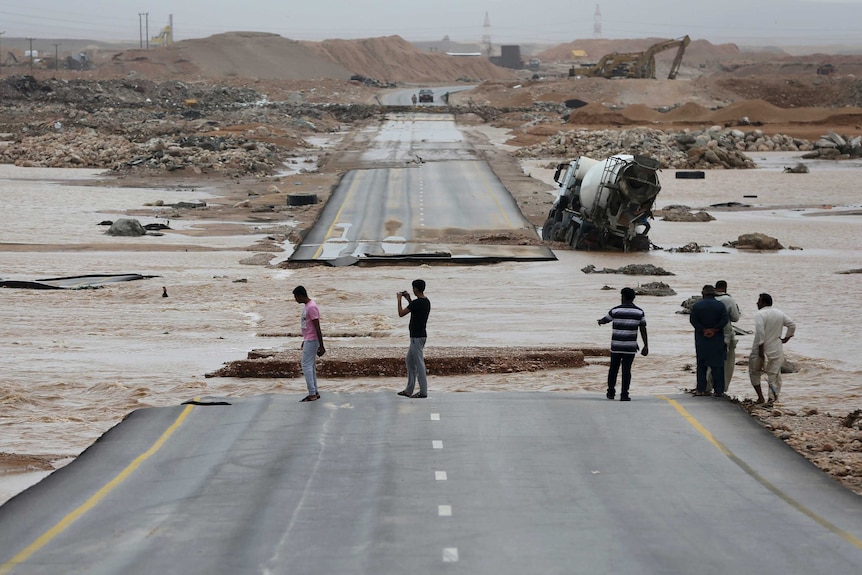 Debris is scattered and a road is damaged by flood waters.