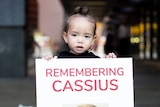 A young girl holding a poster saying 'Remembering Cassius".