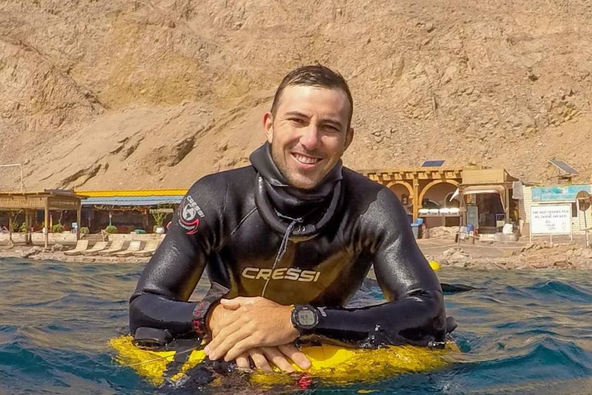 Homme souriant sur un flotteur dans l'eau.