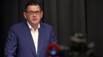 A man in a suit stands at a lectern