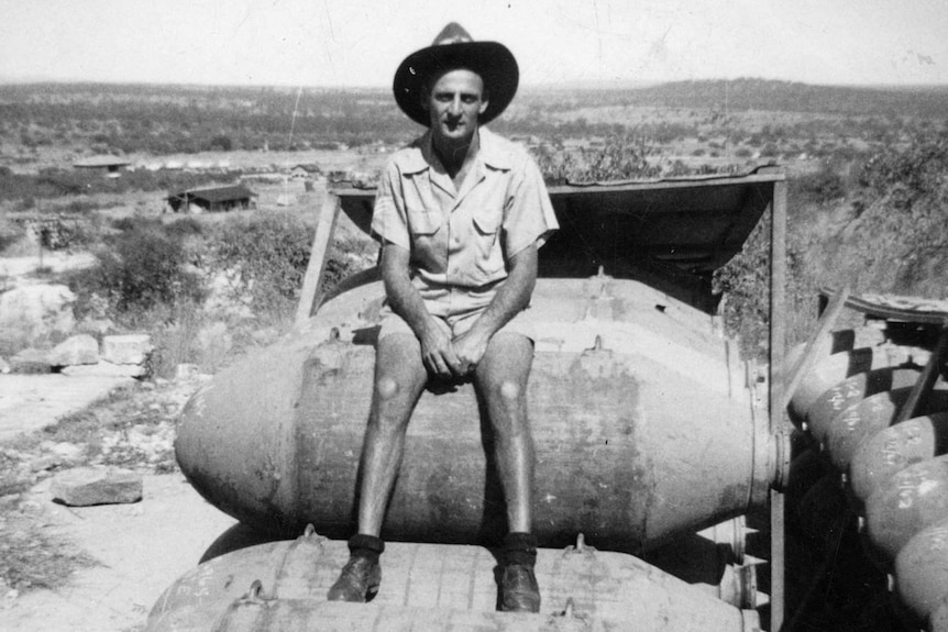 a serviceman sits on a stack of bombs