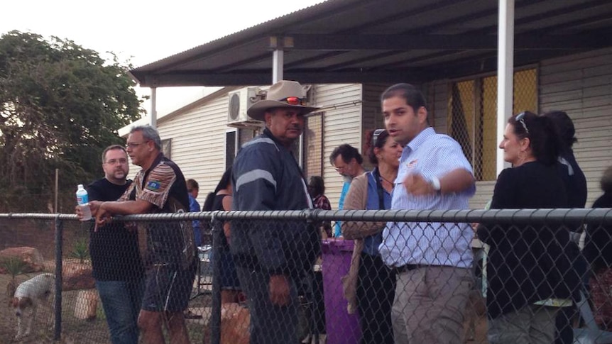 A man in a cowboy hat stares at the camera while another man points at the camera.