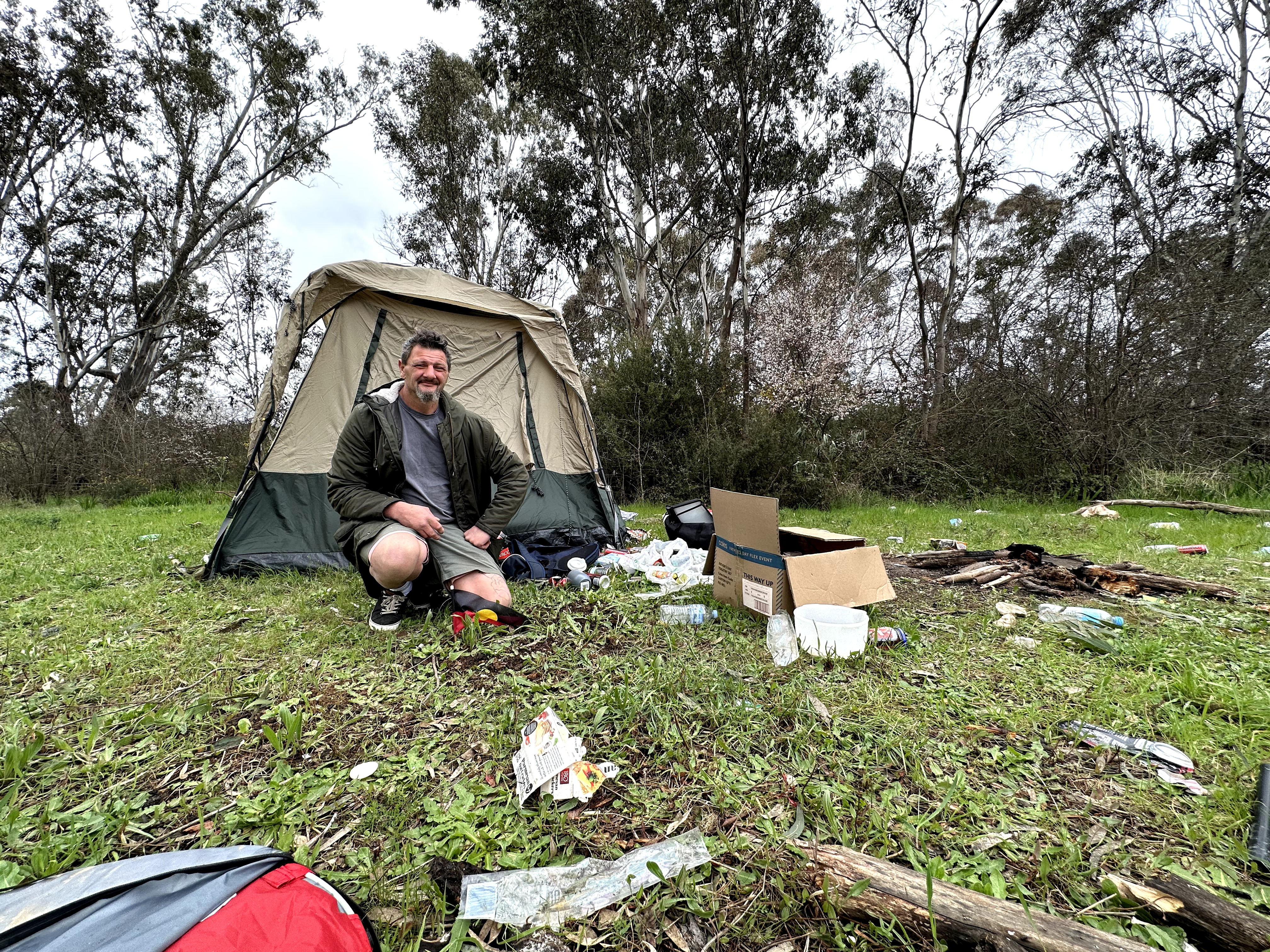 a man kneels beside a tent