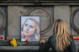 A woman places flowers next to a portrait of slain television reporter Viktoria Marinova.