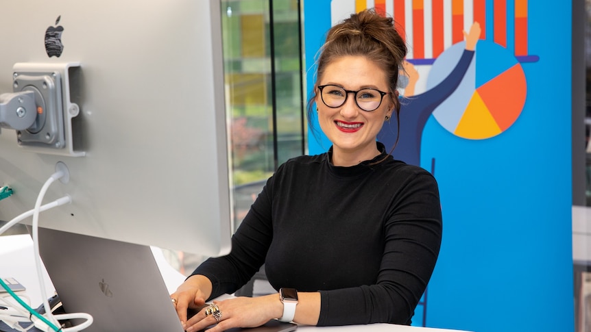 Employee Kirsti Taylor sits at her computer at her employer's new office.