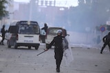 Riot policemen walk on a road amid tear gas during a protest in Kasserine.