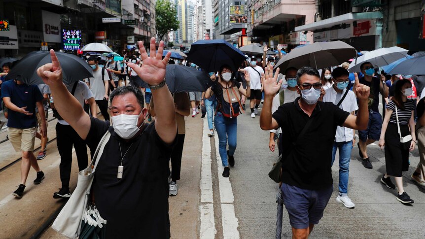 Protesters holding up six fingers at a protest in Hong Kong signifying their five demands, and not one less.