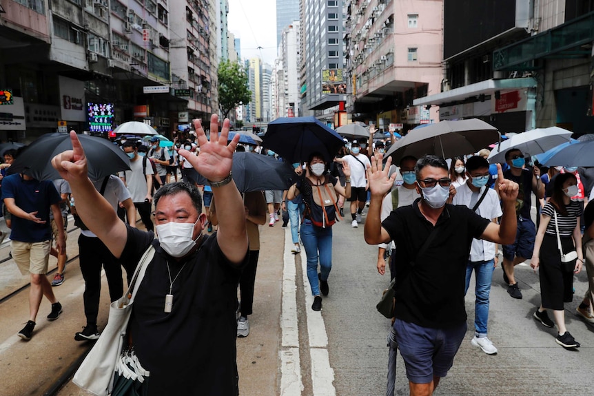 Protesters holding up six fingers at a protest in Hong Kong signifying their five demands, and not one less.