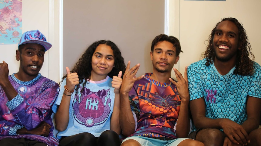 Four highly accomplished Indigenous teenagers sitting on a couch together looking at the camera smiling.