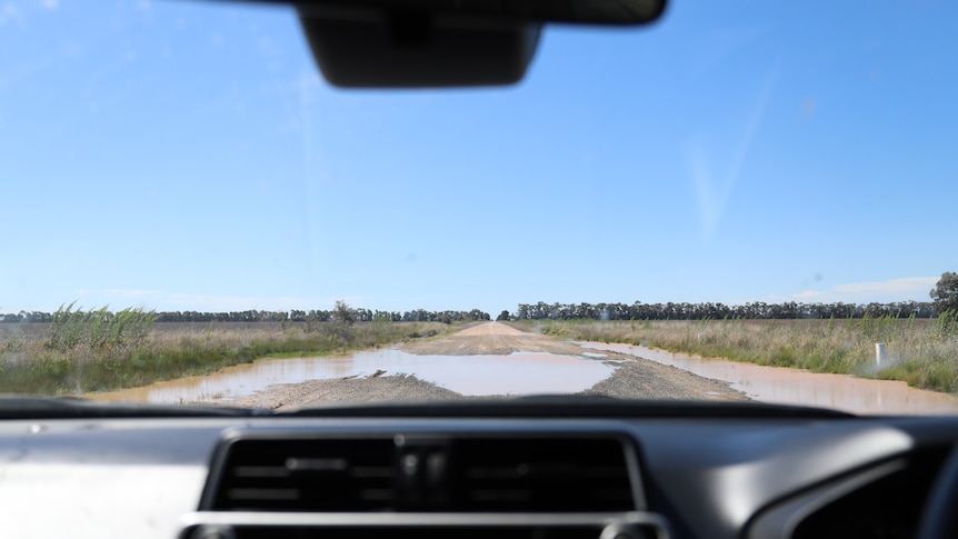 A flooded road, photographed through the windscreen of a car.