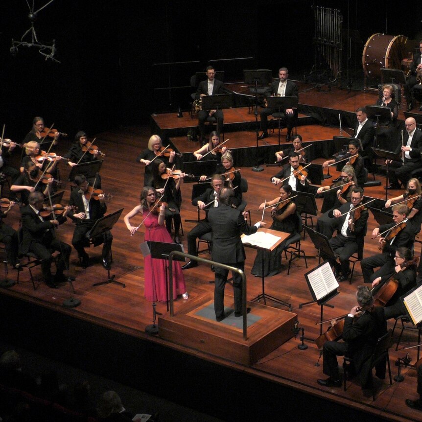 Violinist Emma McGrath playing in front of an orchestra  