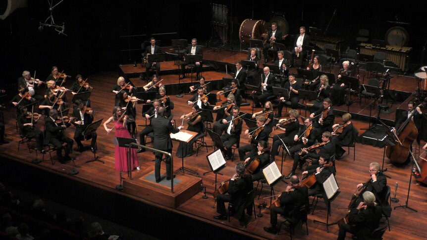 Violinist Emma McGrath playing in front of an orchestra  
