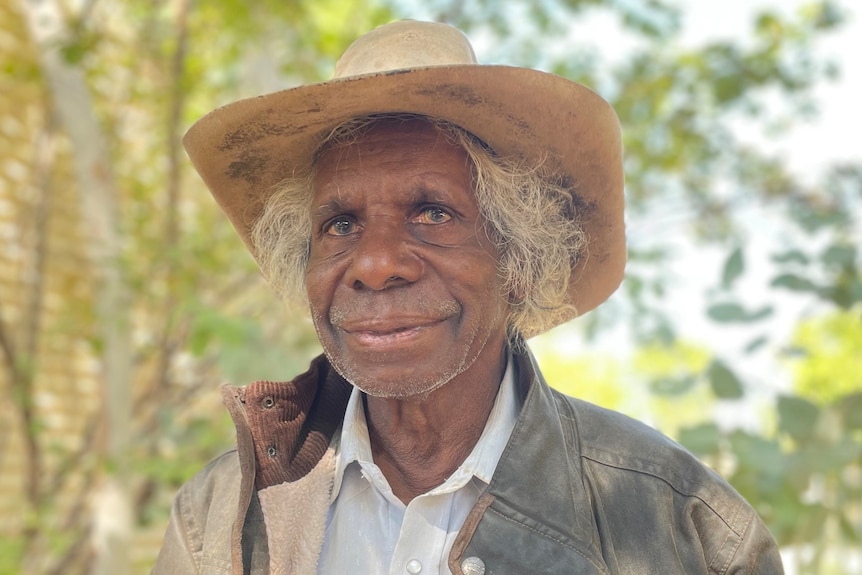 A man in a hat smiles at the camera